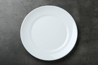 Gri masadaki boş beyaz seramik tabak, üst görünüm