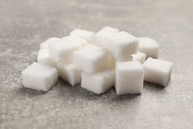 Gri masada bir sürü küp şeker, yakın plan.