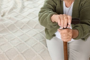 Elderly woman with walking cane indoors, closeup. Home care service