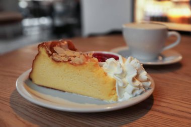 Delicious dessert and cup of aromatic coffee on wooden table in cafe, closeup