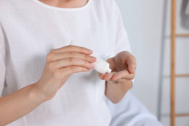 Kadın elinde tüpten krem sürüyor, kapalı alanda, yakın plan.