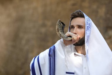 Yahudi bir adam Rosh Hashanah 'ı açık havada uçuruyor. Evrenin hükümdarı, bizi emirleriyle kutsayan ve kendimizi İbranice Tzitziton 'a sarmamızı emreden Tanrı' mız, sen kutsanmış olansın.