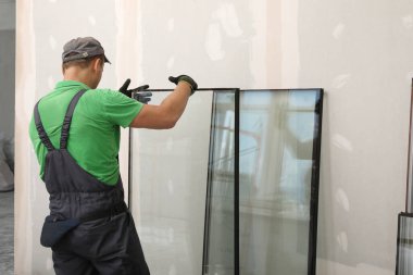 Üniformalı işçiler çift camlı pencere hazırlıyorlar.