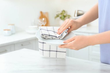 Kadın mutfakta havluyla tabağı siliyor, yakın plan.