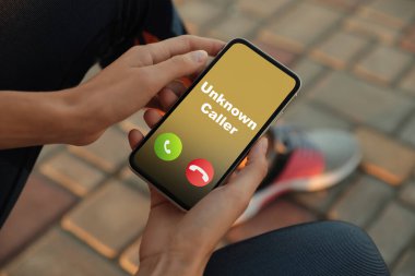 Elinde akıllı telefon tutan bir kadın. Dışarıdan aranan bilinmeyen biri tarafından aranmış. Yakın plan. Dikkatli ol, sahtekar.