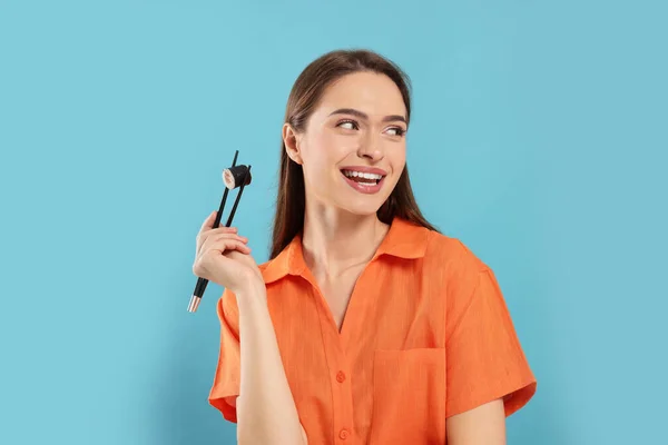 Glad Ung Kvinna Som Håller Sushi Rulle Med Ätpinnar Ljusblå — Stockfoto