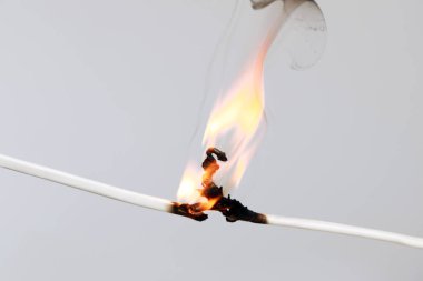 Gri arka planda iltihaplı beyaz kablo, yakın plan. Elektrik kısa devresi