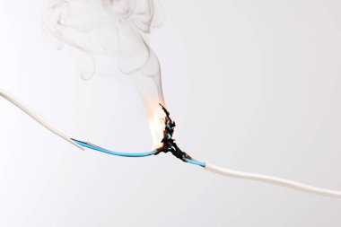 Gri arka planda iltihaplı beyaz kablo, yakın plan. Elektrik kısa devresi