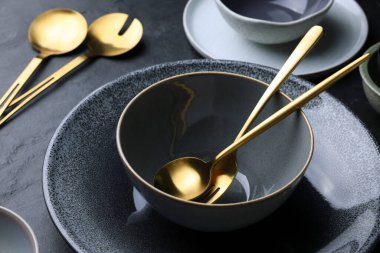 Set of clean tableware on black table, closeup