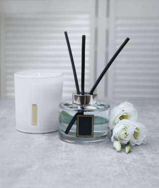 Reed diffuser, scented candle and eustoma flowers on gray marble table