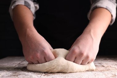 Ahşap masada hamuru yoğuran adam karanlık arka planda, yakın plan