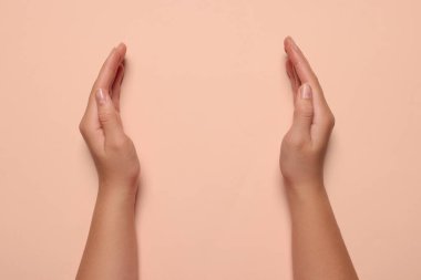 Soluk pembe arka planı olan bir kadın, elleri yakın çekim. Metin için boşluk