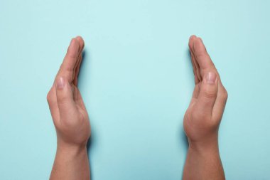 Turkuvaz arka planda tutulan bir kadın, ellerin yakın çekimi. Metin için boşluk