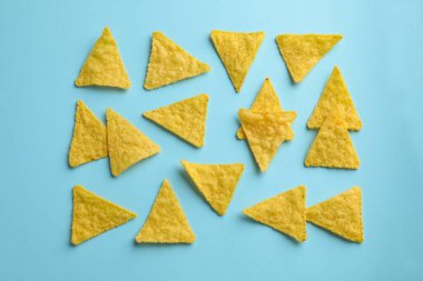Açık mavi zemin üzerinde lezzetli tortilla cipslerinin (nachos) düzleştirilmiş bileşimi