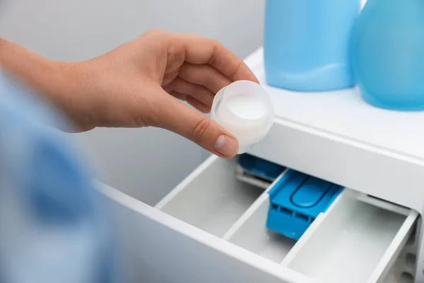 Woman pouring laundry detergent into drawer of washing machine, closeup