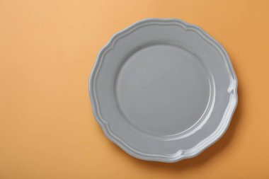 Soluk turuncu arka planda boş seramik plaka, üst manzara. Metin için boşluk