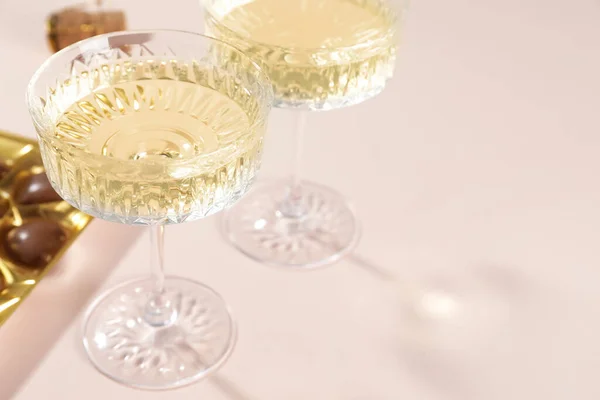 Glasses of expensive white wine on pink background, closeup. Space for text