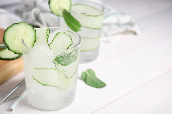 Tasty fresh cucumber water with mint on white wooden table, closeup. Space for text
