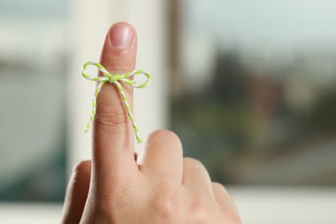 Bulanık arkaplanda hatırlatıcı olarak bağlı işaret parmağı gösteren adam, yakın plan