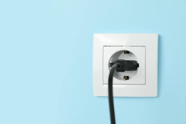Açık mavi duvara yerleştirilmiş prizi olan güç soketi, metin için boşluk. Elektrik arzı