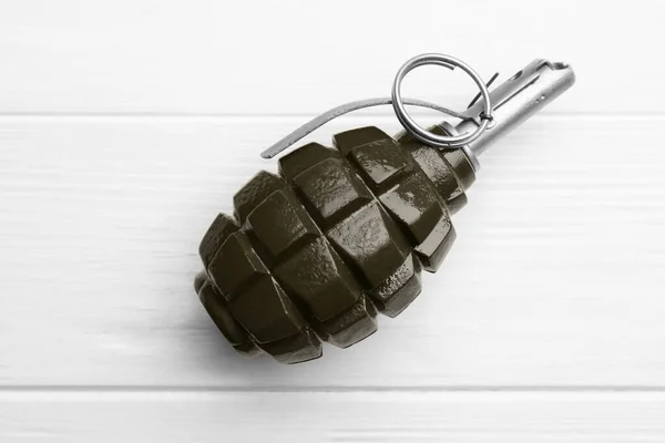 Hand grenade on white wooden table, top view