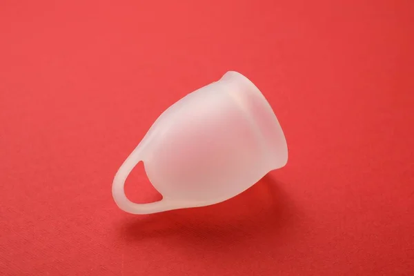 Menstrual cup on red background. Reusable female hygiene product