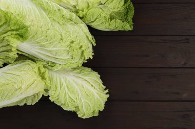 Fresh ripe Chinese cabbages on dark wooden table, fat lay. Space for text