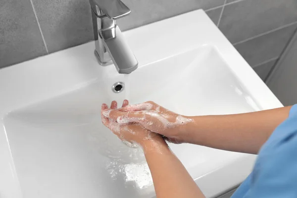 Doctor washing hands with water from tap in bathroom, above view
