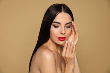 Bej arka planda güzel kırmızı ruj süren genç bir kadının portresi.