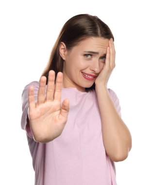 Utanmış genç bir kadın beyaz arka planda yüzünü kapatıyor.