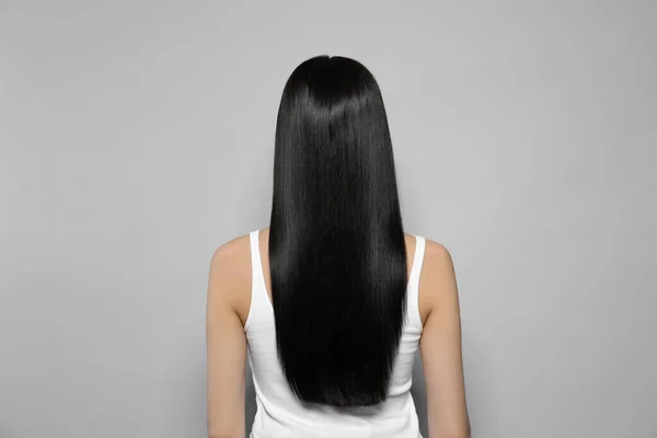 Młoda Kobieta Długimi Prostymi Włosami Szarym Tle Widok Tyłu — Zdjęcie stockowe