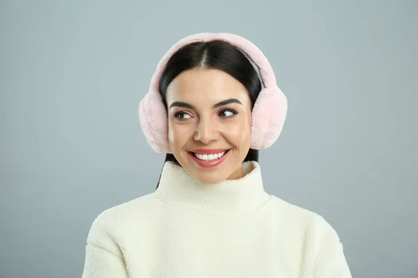 美しいです若いです女性身に着けていますEarmuff上のライトグレーの背景 — ストック写真