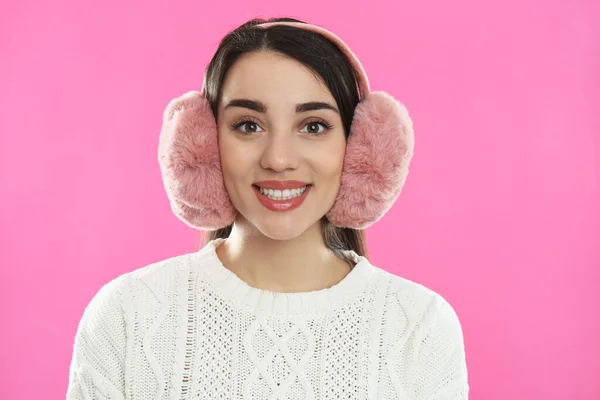 美しいです若いです女性身に着けていますEarmuff上のピンクの背景 — ストック写真