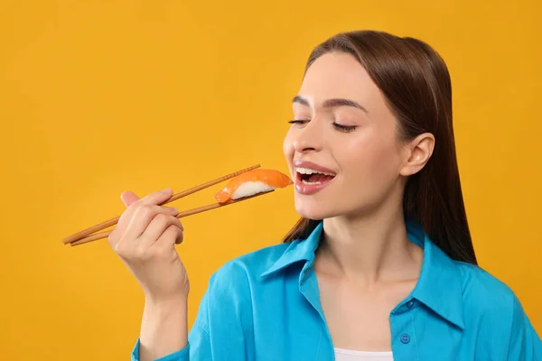 Vacker Ung Kvinna Äter Sushi Med Ätpinnar Orange Bakgrund — Stockfoto