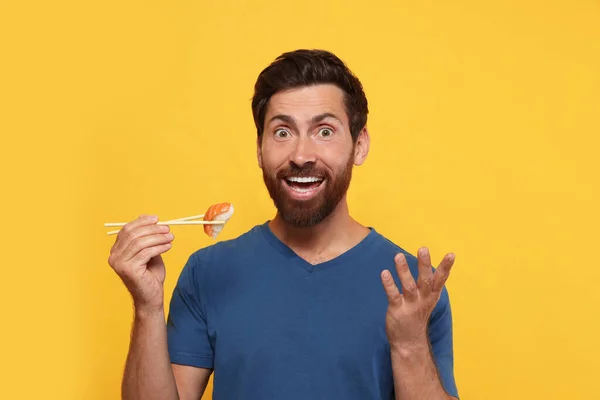 Emotional Man Holding Sushi Chopsticks Orange Background — Stock Photo, Image