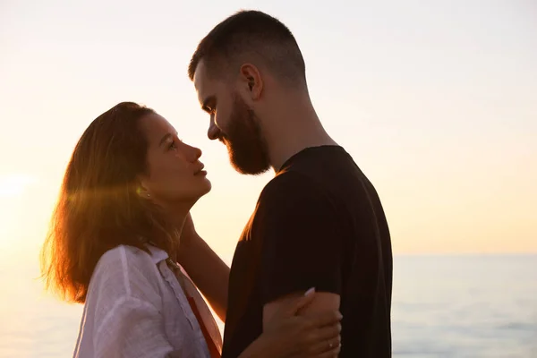 快乐的年轻夫妇在日落时在海边接吻 — 图库照片