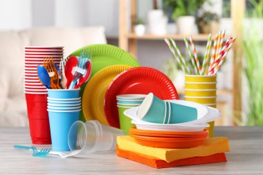 Parlak tek kullanımlık sofra takımı. İçerideki ahşap masa üzerinde.