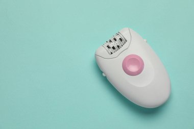 Turkuaz arka plan, üst görünüm üzerine modern epilatör. Metin için boşluk