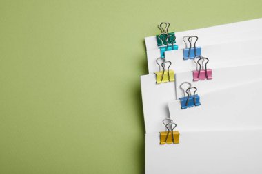 Açık yeşil arka planda ataçları olan kâğıtlar, üst manzara. Metin için boşluk