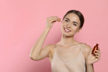 Pembe arkaplan üzerine gerekli yağı uygulayan genç bir kadın, metin için boşluk