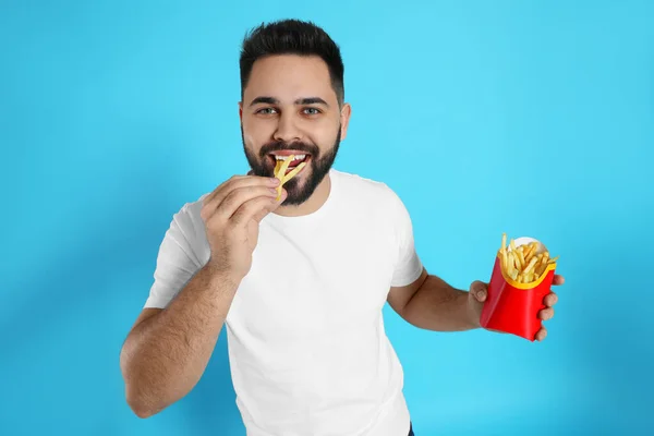 Young Man Eating French Fries Light Blue Background — Stock Photo, Image
