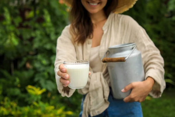 Smiling woman holding can and glass with fresh milk, closeup