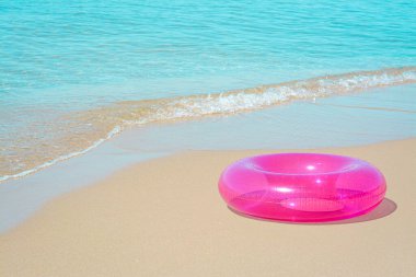 Deniz kenarındaki kumlu sahilde parlak şişirilebilir bir yüzük. Metin için boşluk