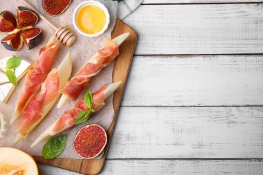 Lezzetli kavun, jambon ve incir, beyaz ahşap masada servis ediliyor. Metin için boşluk