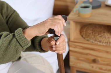 Elderly woman with walking cane indoors, closeup. Home care service