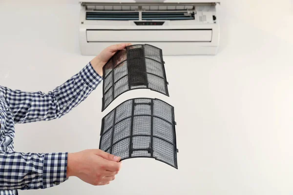Man cleaning air conditioner filters indoors, closeup