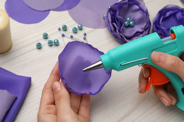 Woman with hot glue gun making craft at wooden table, closeup