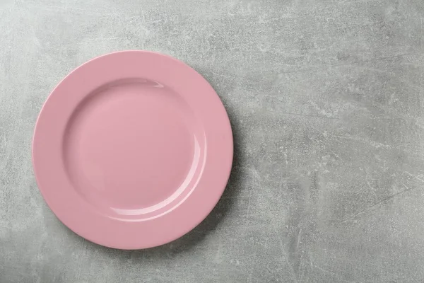 Clean pink plate on grey table, top view. Space for text