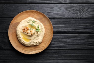 Siyah ahşap masa üzerinde nohut bulunan bir kase lezzetli humus. Metin için boşluk