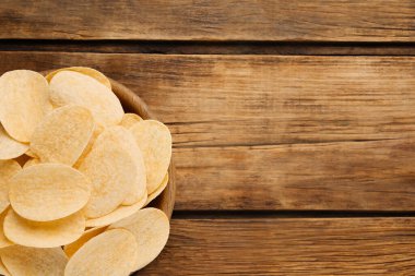 Tahta masanın üstünde patates cipsi olan bir kase, en iyi manzara. Metin için boşluk